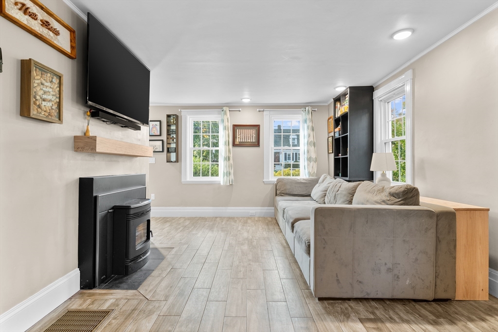 Living room with a gray sectional, black fireplace, wall-mounted TV, and three bright windows.