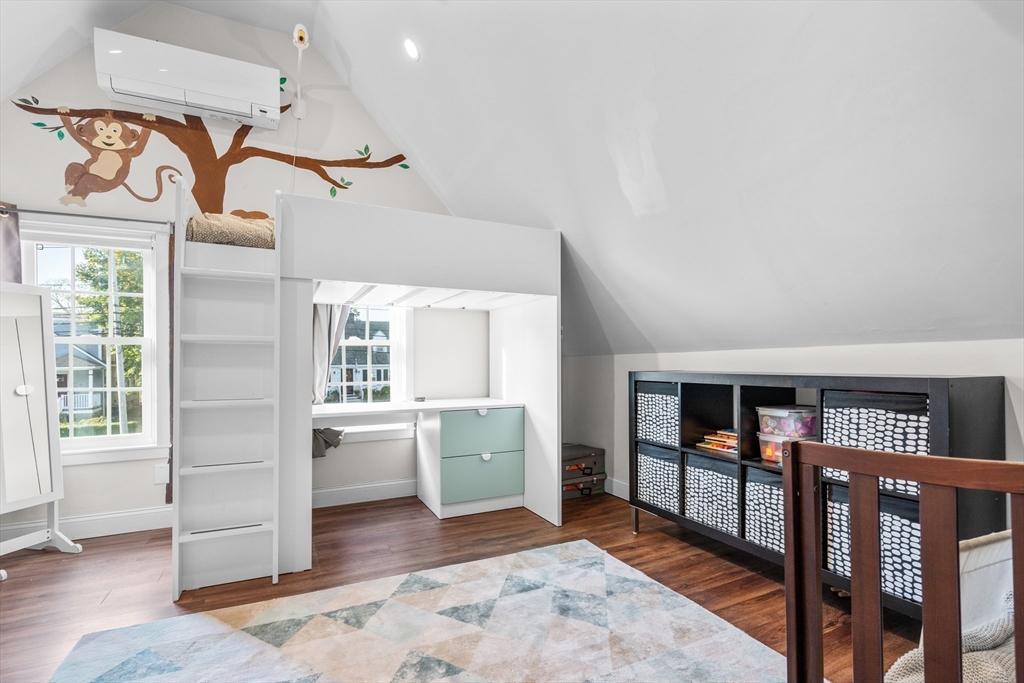 Attic bedroom with a built-in loft bed and desk beneath a sloped ceiling.