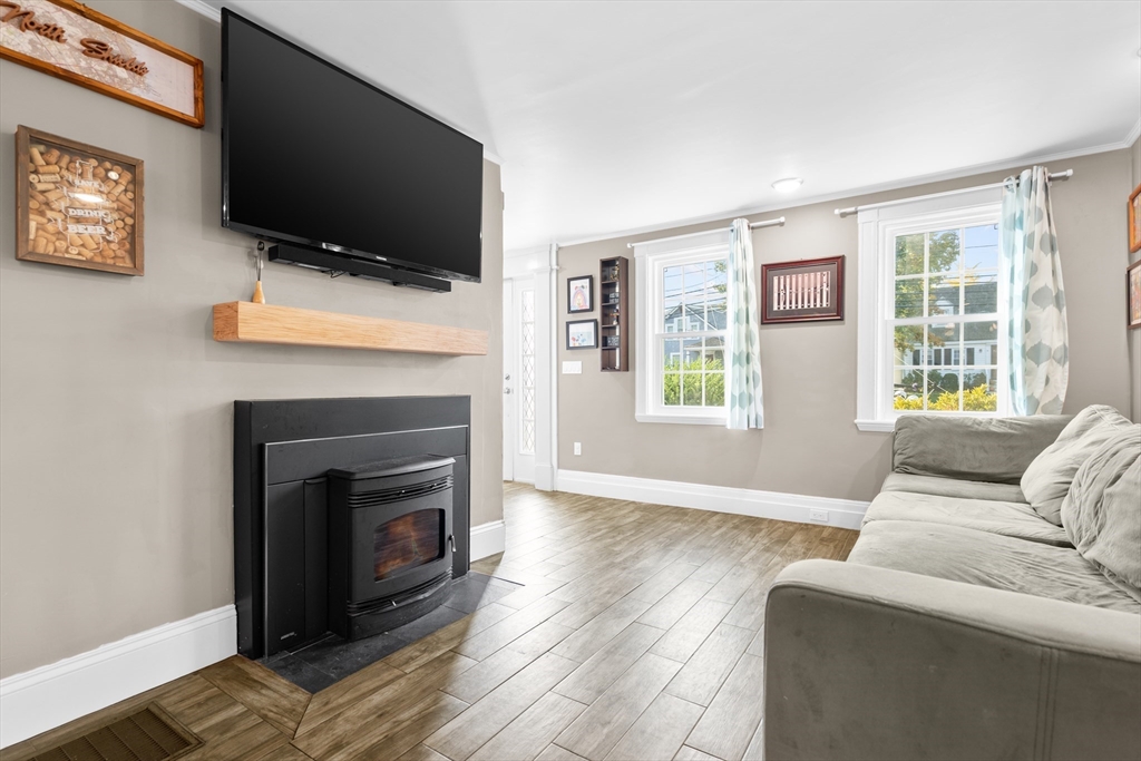 Living room with a gray sectional, black pellet stove, and wall-mounted television.