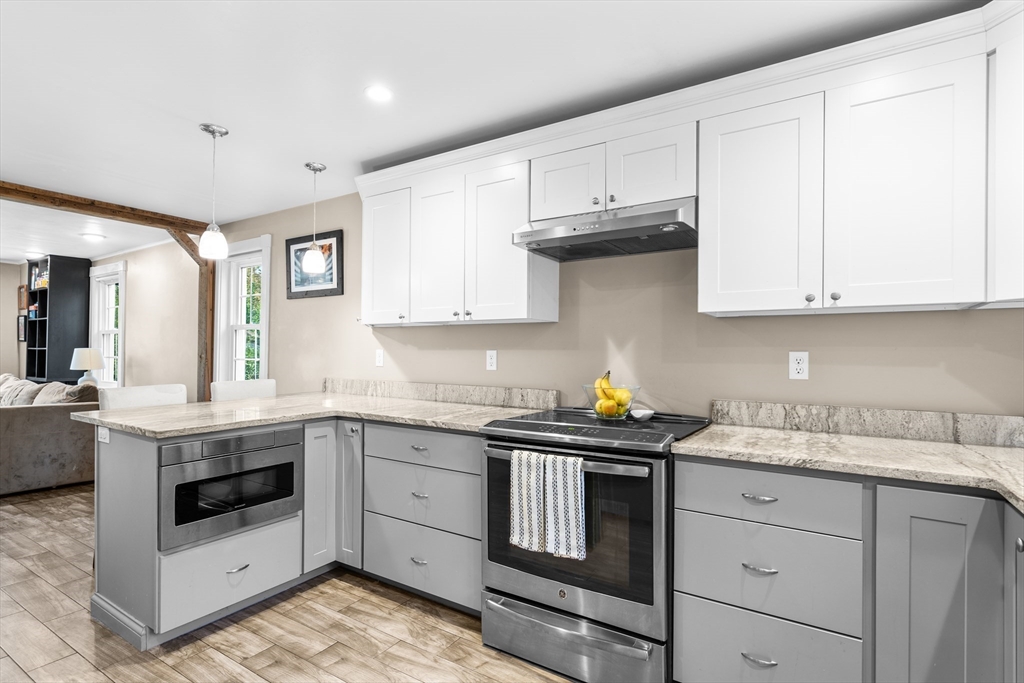 Kitchen with white cabinets, gray drawers, stone-look counters, and stainless steel appliances.
