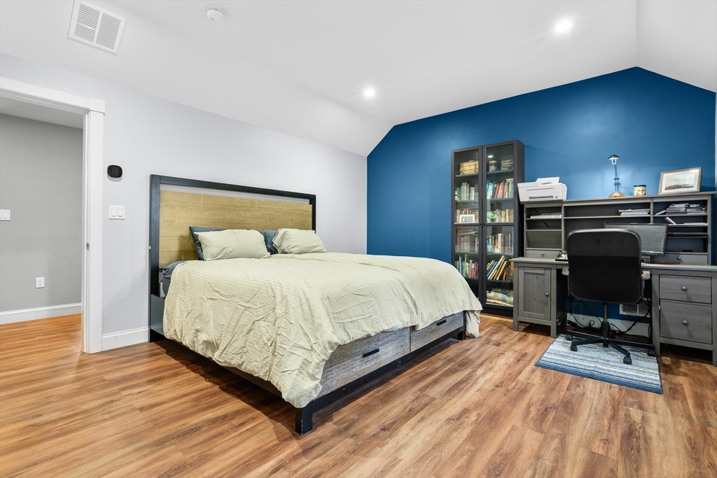Bedroom with a large bed, blue accent wall, and desk with bookshelves and a computer.