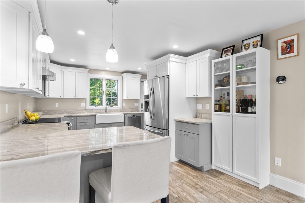 Bright kitchen with a marble island, white cabinets, stainless appliances, and a farmhouse sink.