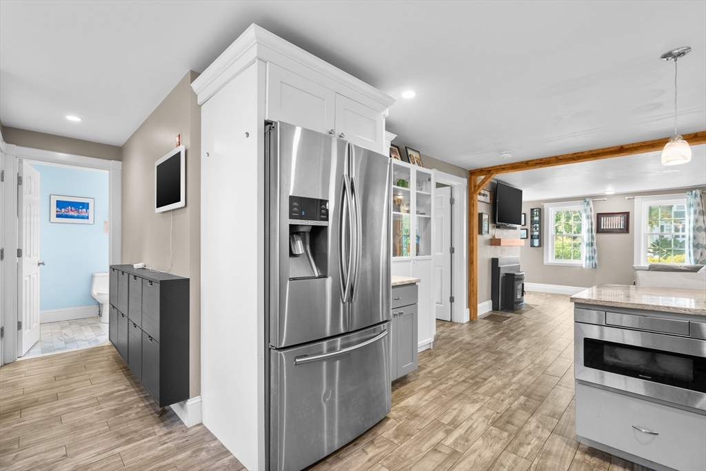 Kitchen with stainless steel refrigerator, white cabinetry, and gray island opening to a bright living area.