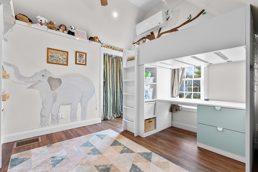 Child's bedroom with a built-in loft bed and desk, elephant mural, and stuffed animals on a high shelf.
