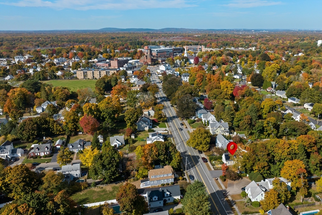 Aerial neighborhood view with a red marker identifying a home beside the main road.