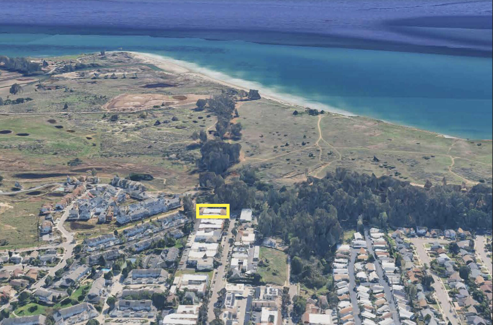 Aerial view of the marked property near the beach, with the Pacific Ocean beyond.