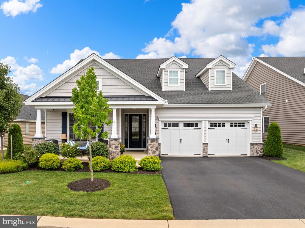 Light gray two-story home with a covered porch, dormer windows, and a three-car garage.