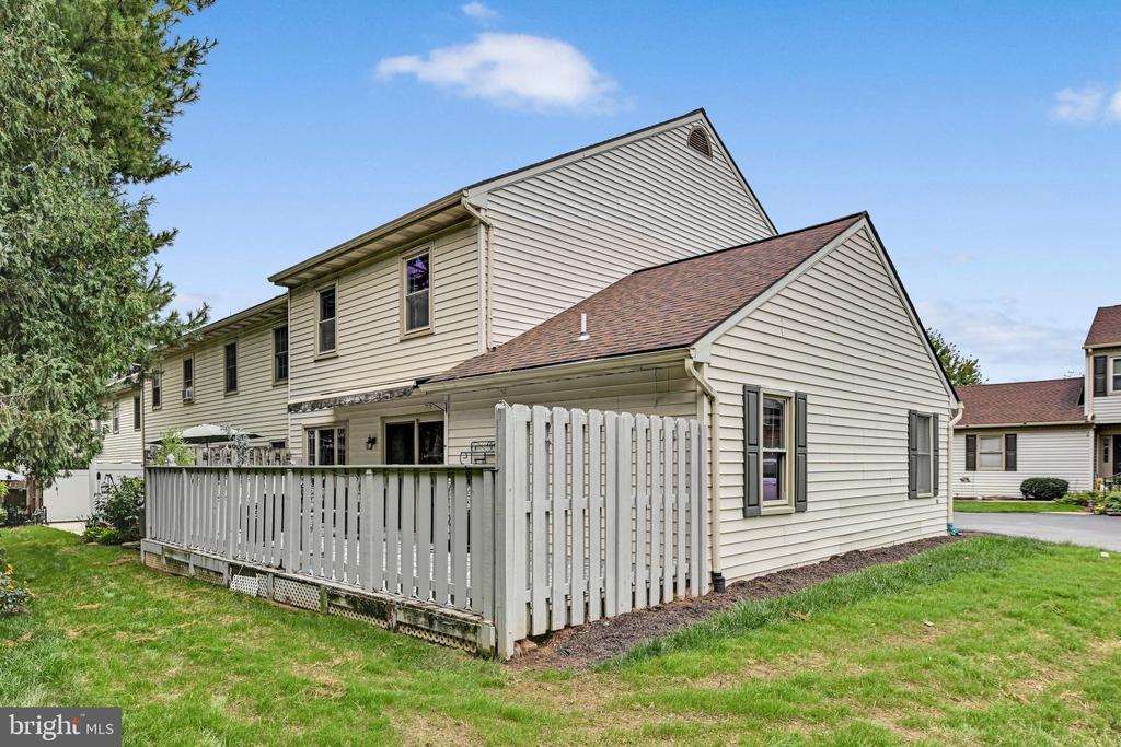 Beige two-story townhouse with a fenced patio and lawn.