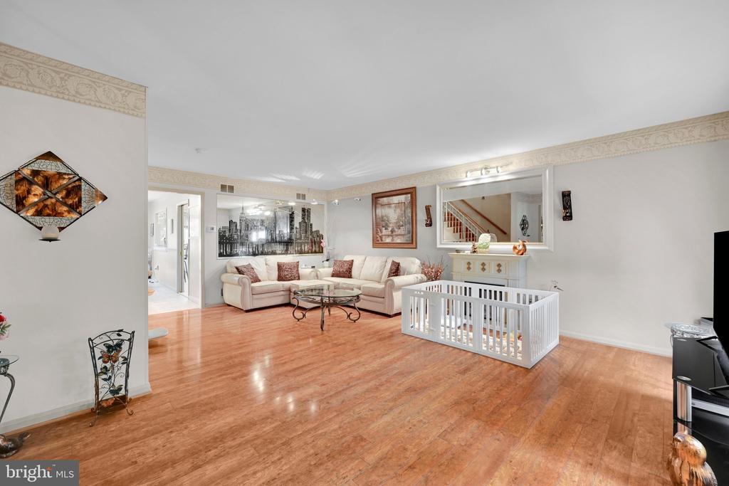 Living room with a cream sectional, hardwood floors, and a white playpen.