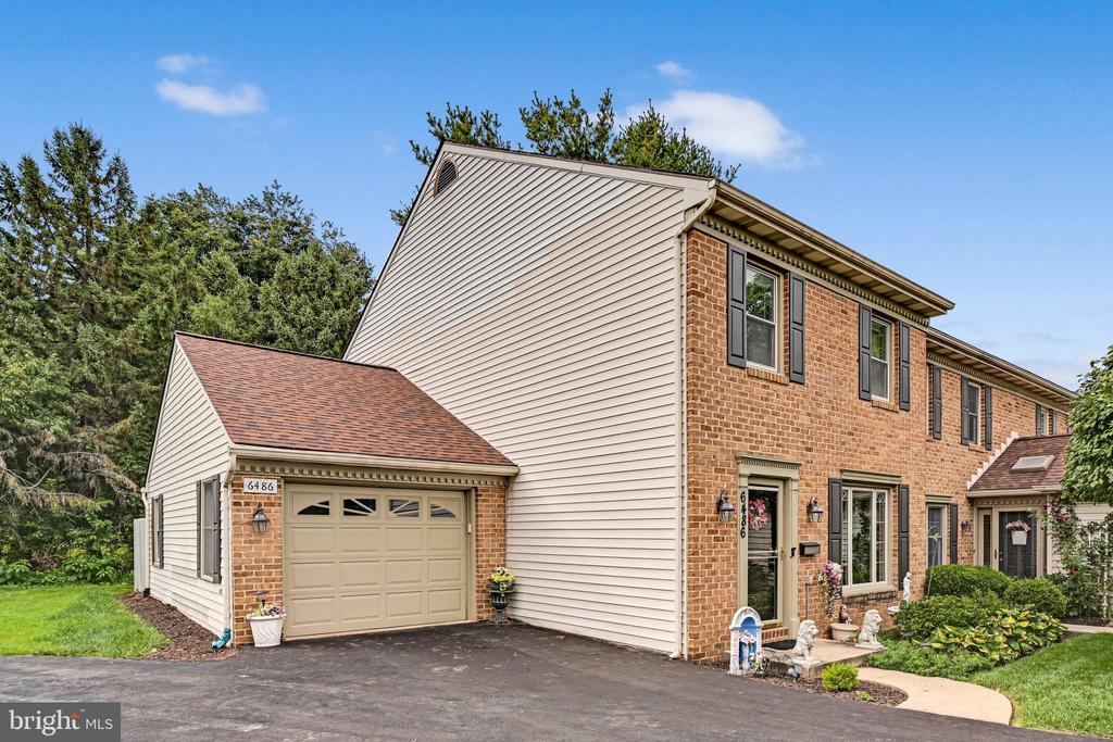 Two-story brick-and-vinyl townhouse with an attached garage and landscaped front yard.