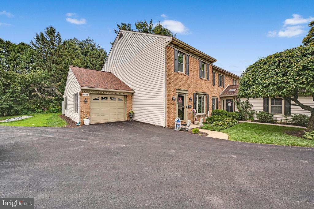 Two-story brick and siding townhouse with an attached garage and broad paved driveway.