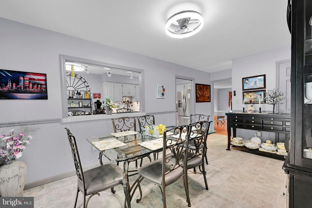Dining room with a glass-top table, ornate metal chairs, and a pass-through to the kitchen.