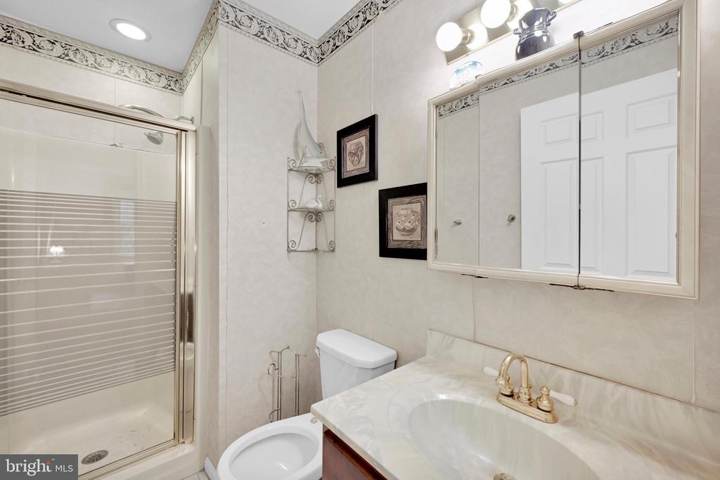 Bathroom with glass shower, marble-look vanity, and mirrored medicine cabinet.