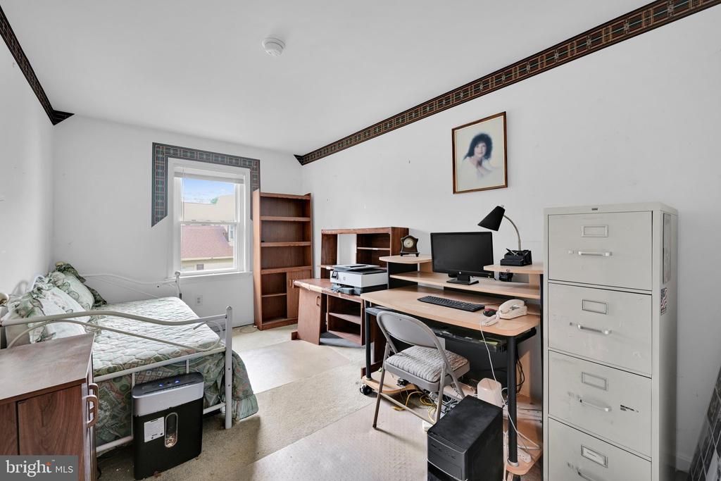 Bedroom home office with a bed, computer desk, bookshelves, and decorative ceiling trim.
