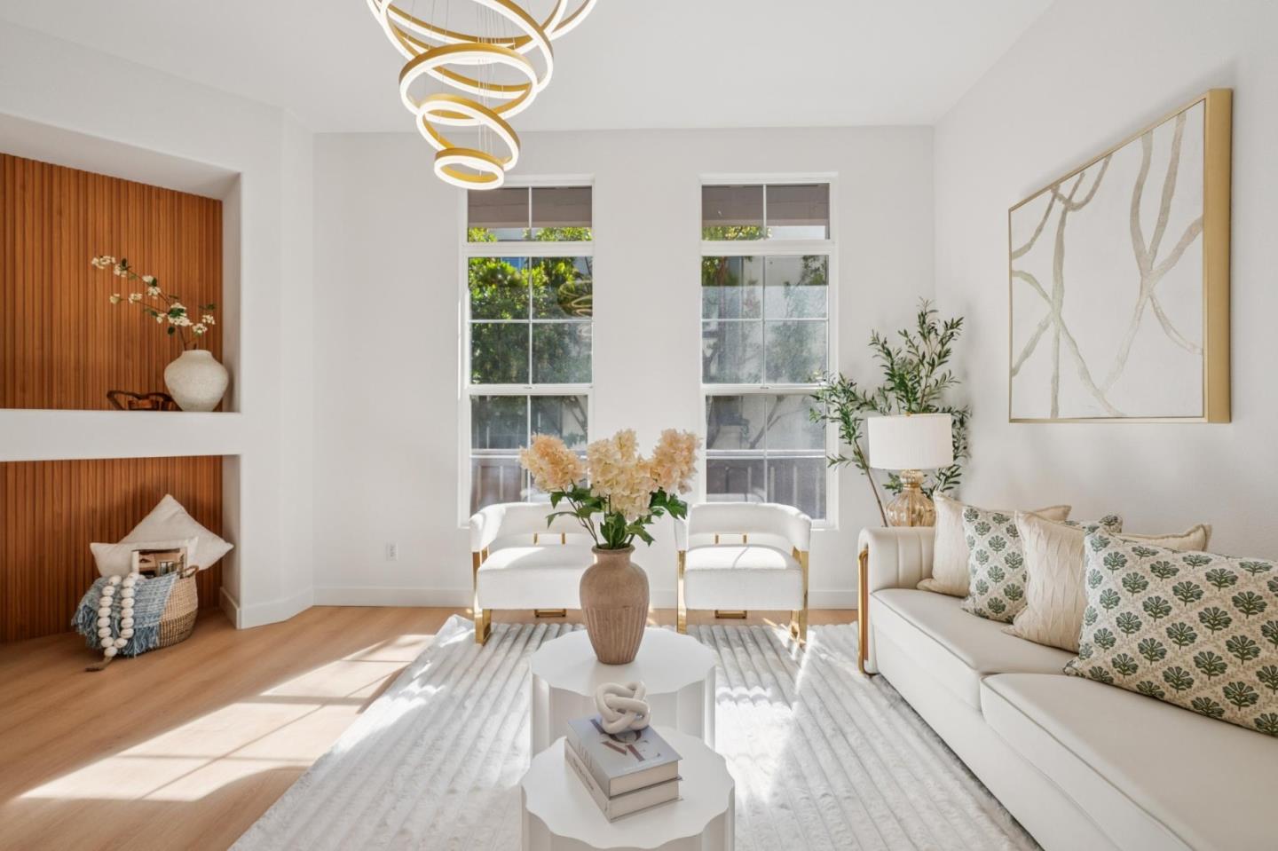Staged living room with a white sofa, wood-paneled niches, and a sculptural ring chandelier.