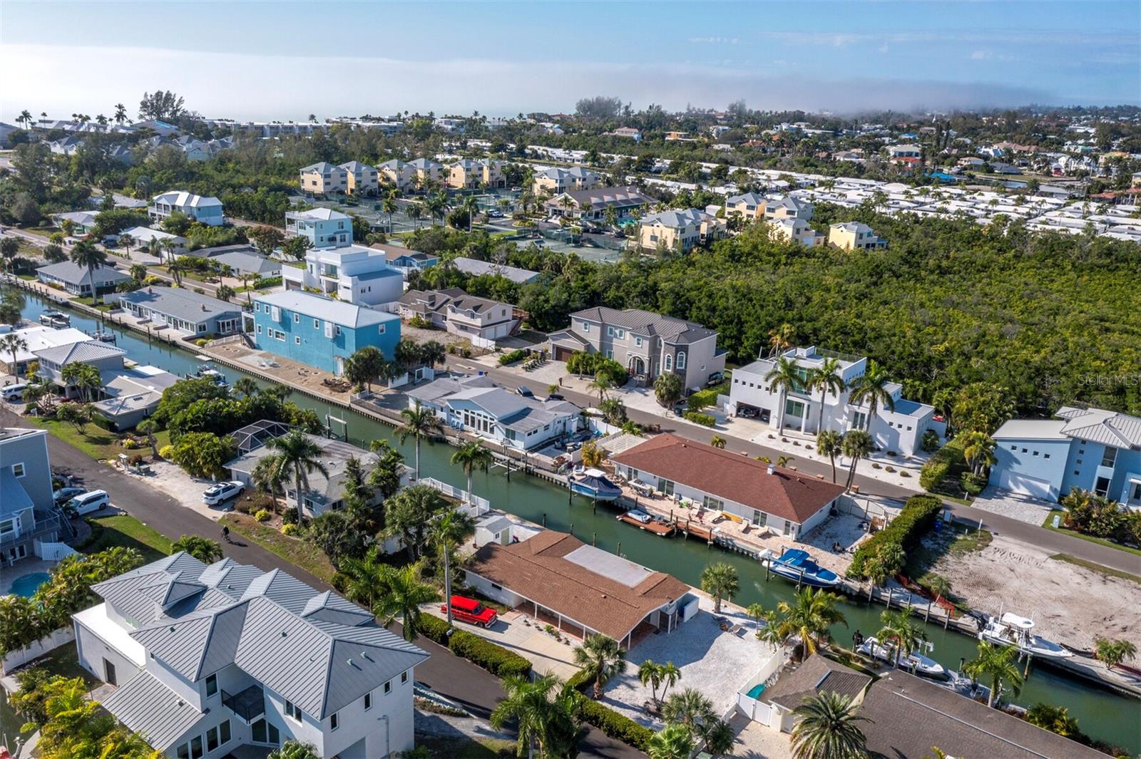 Aerial view of Longboat Key homes along a canal, with boats, docks, and palm trees.