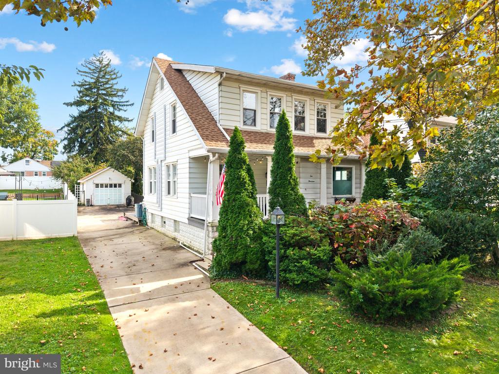 Two-story white-sided home with a covered porch, driveway, and detached garage.