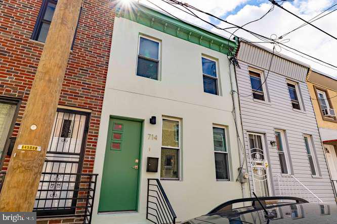 Row house with a pale facade, green front door marked 714, and black entry railings.