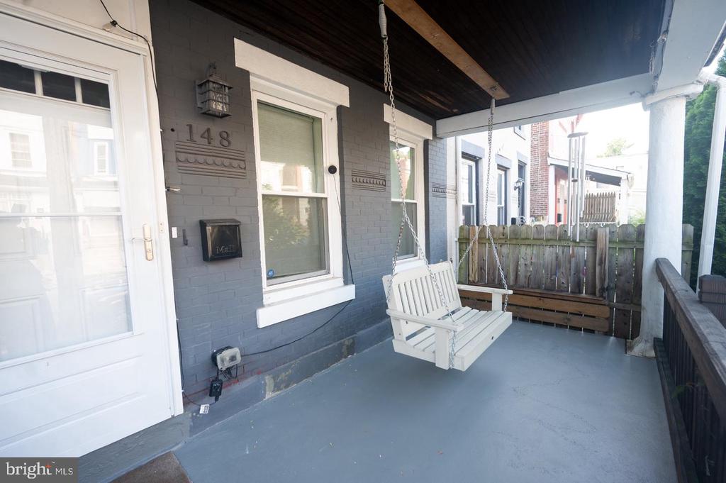 Covered porch with gray brick, white trim, and a hanging white swing.