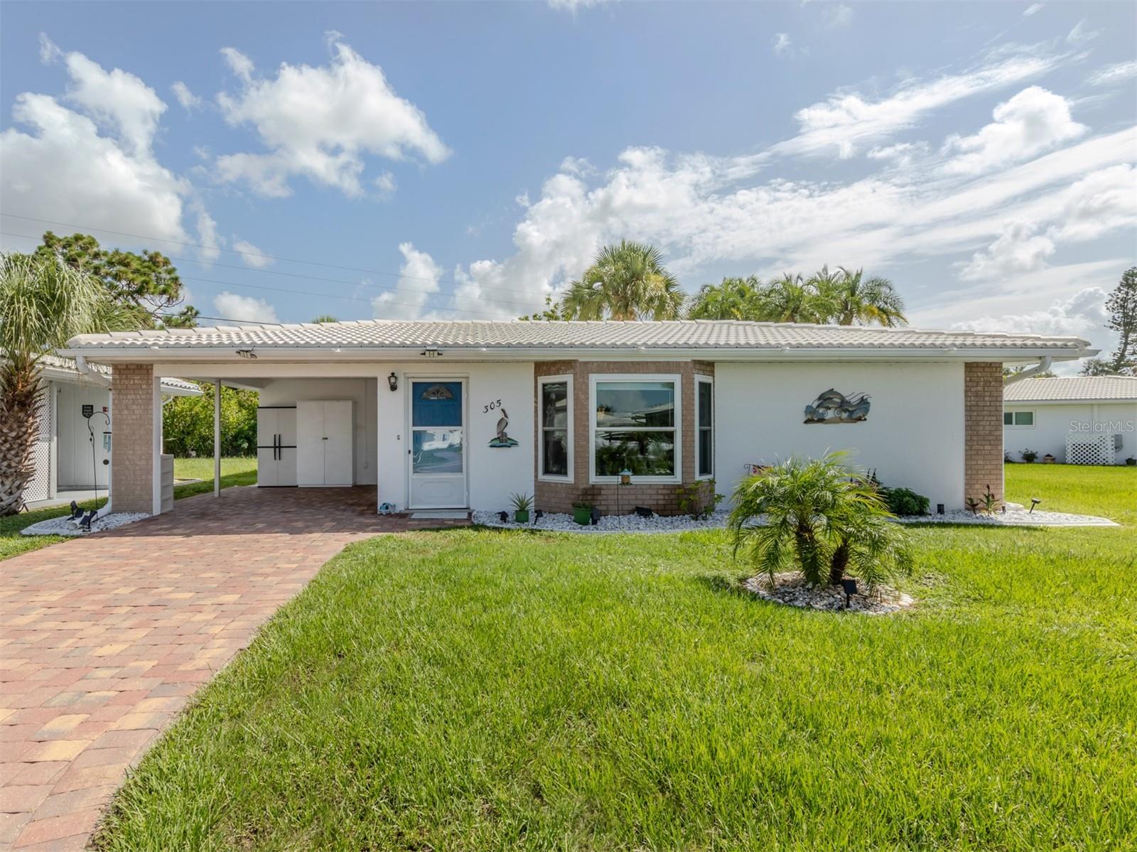 Single-story home with a covered carport, brick-paver driveway, and landscaped front lawn.