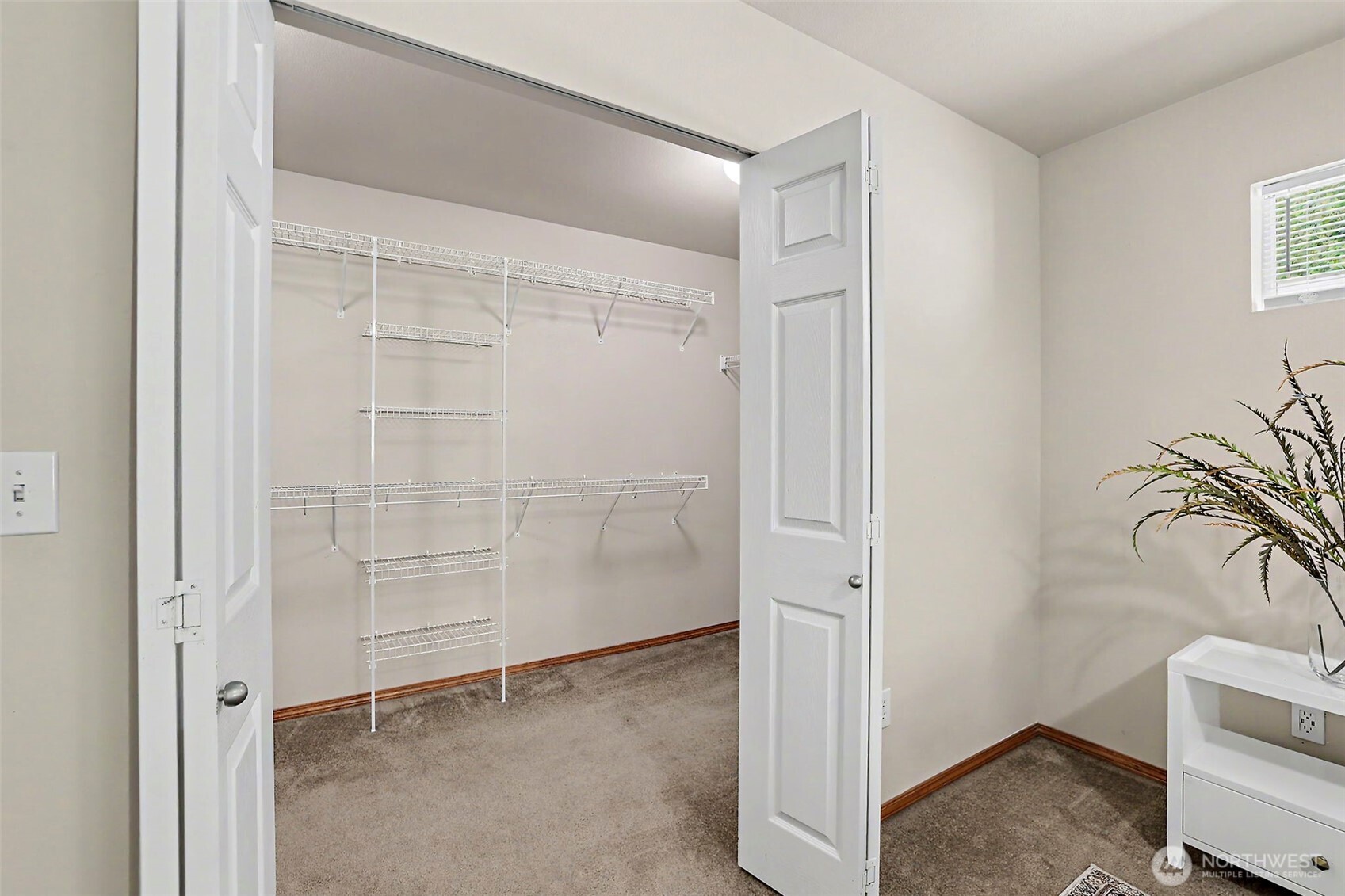 Walk-in closet with empty wire shelving, carpet, and open double doors.