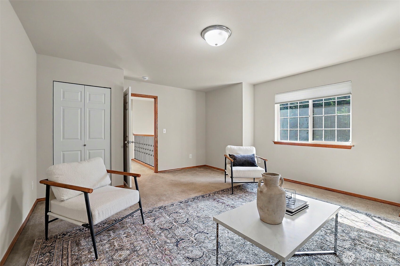 Staged living room with two armchairs, a patterned rug, and a large window.