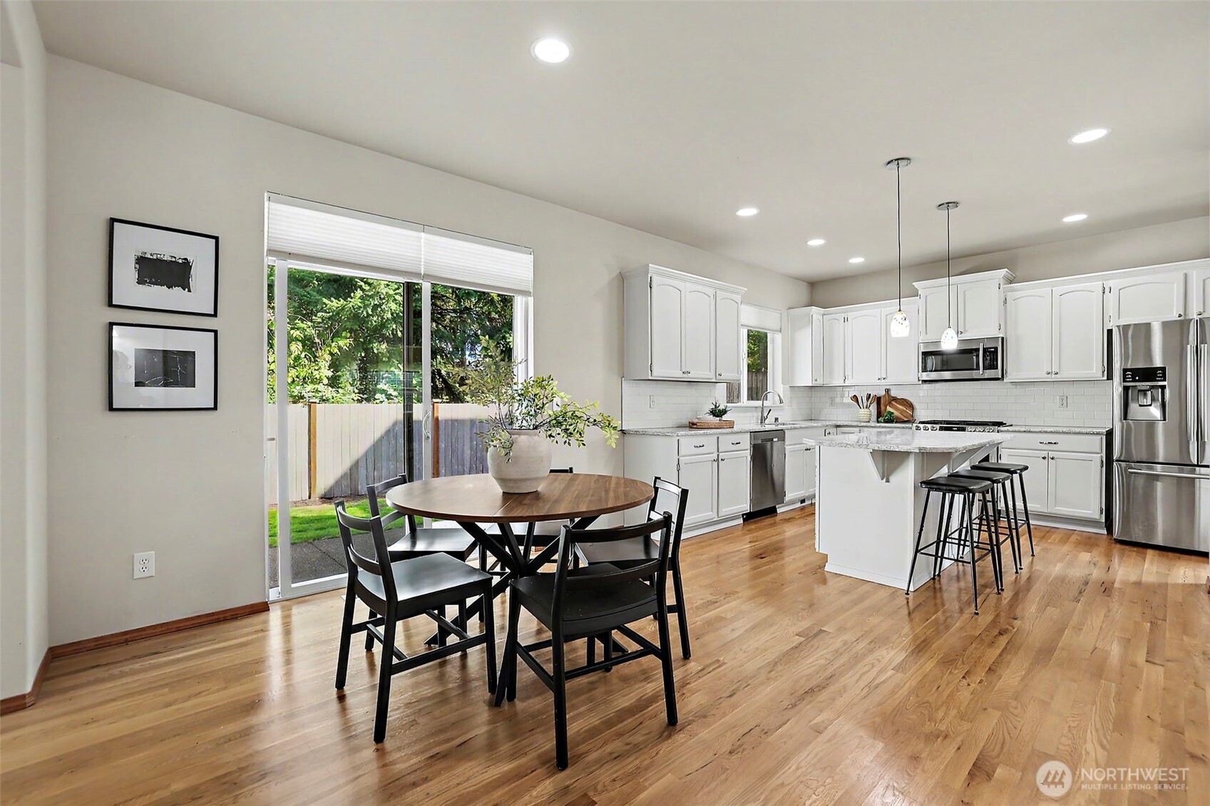Open kitchen and dining area with white cabinetry, a marble-look island, and sliding glass doors to the yard.