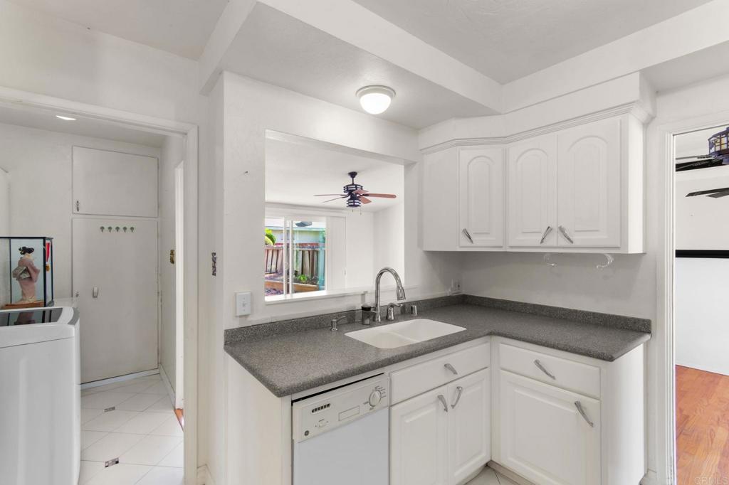 White kitchen with gray counters, a pass-through window, and a laundry area beside it.