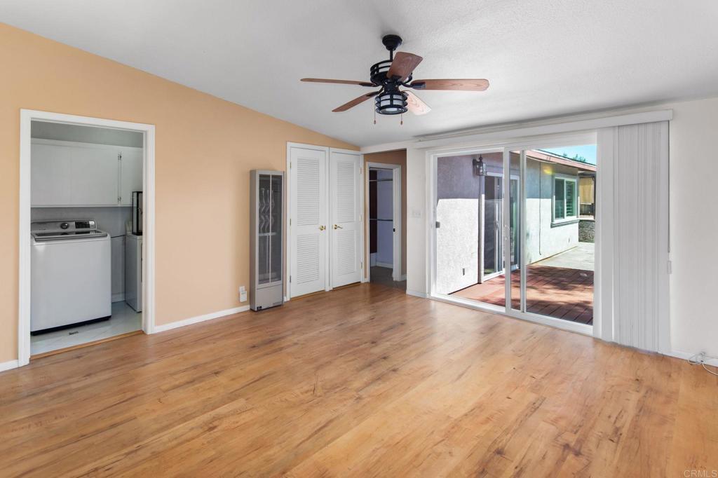 Empty living room with wood floors, ceiling fan, and sliding doors to a patio.