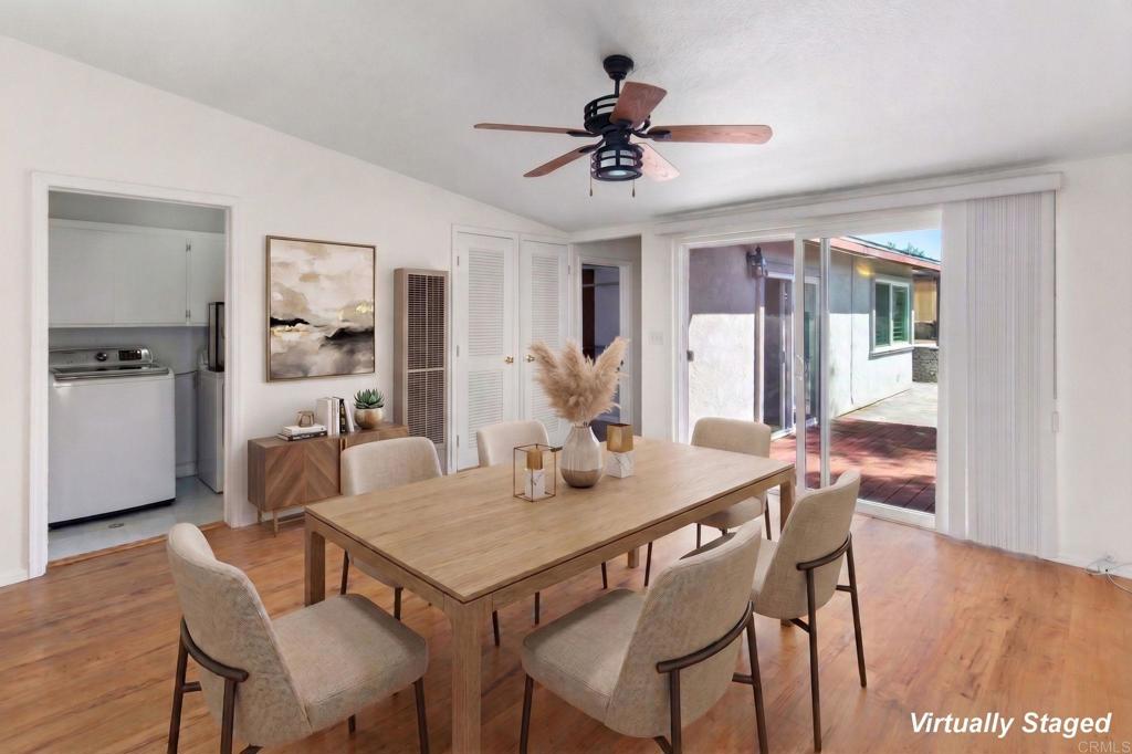 Virtually staged dining room with a wooden table, upholstered chairs, and sliding doors to a patio.
