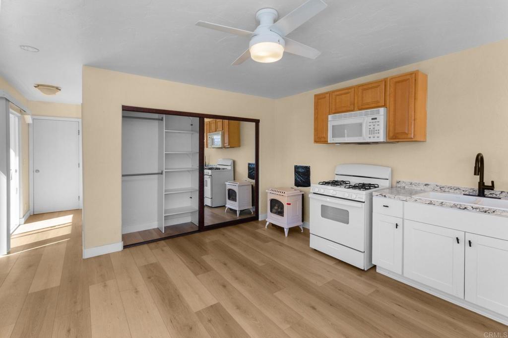 Kitchen with white appliances, wood-tone cabinets, and mirrored sliding doors opening onto a laundry area.