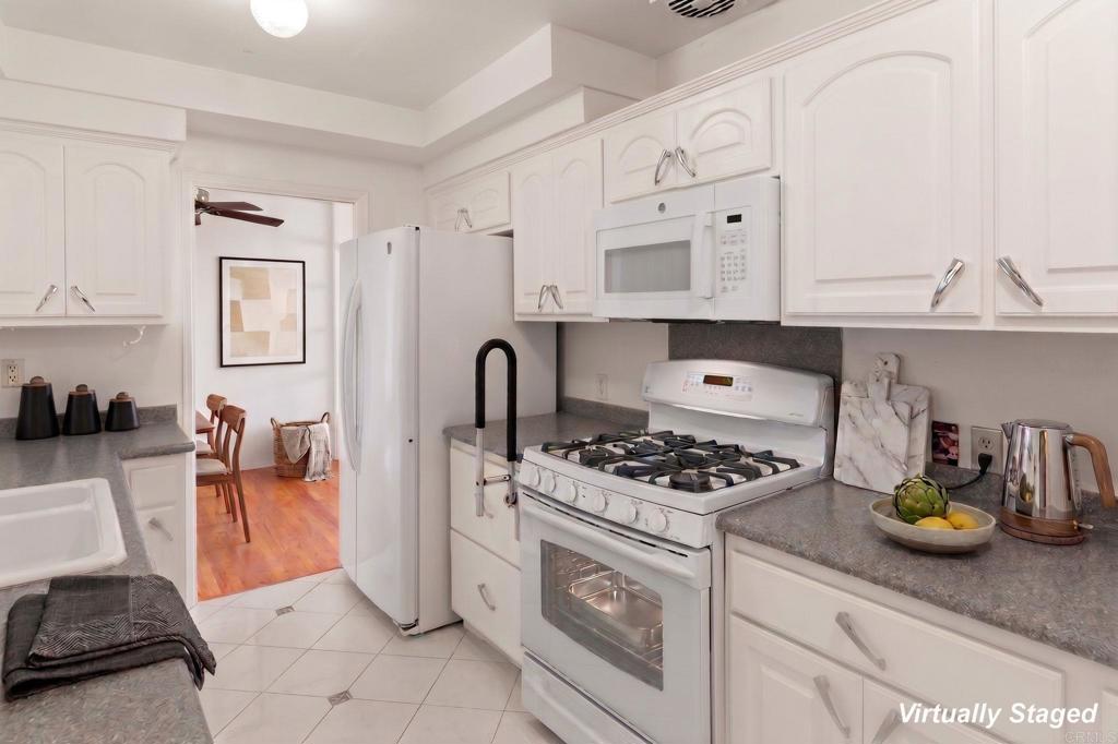 Kitchen with white cabinets, a gas range, built-in microwave, and gray countertops.
