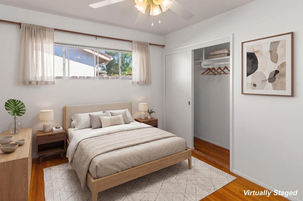 Bedroom with a light wood bed, open closet, sheer-curtained window, and hardwood floors.