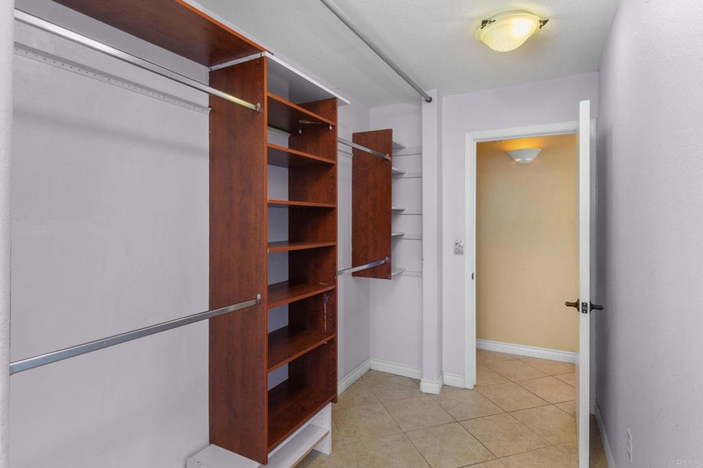 Walk-in closet with built-in wood shelving, hanging rods, and an open doorway.