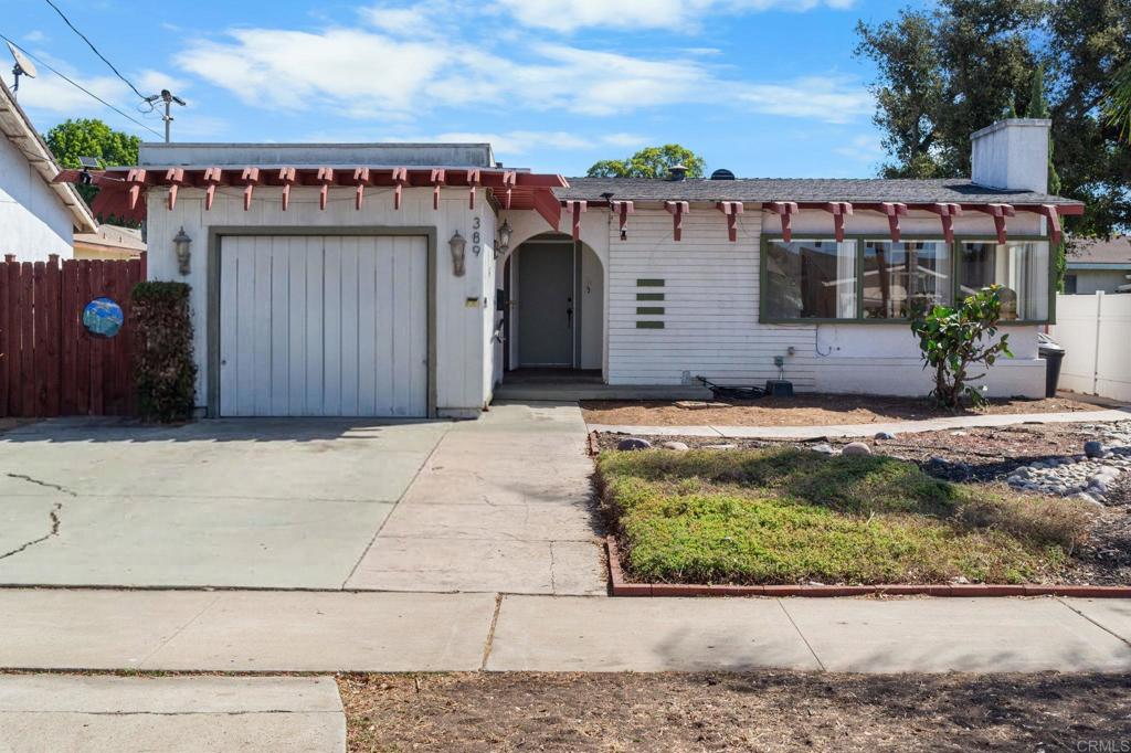 Single-story white house with red roof brackets, attached garage, and broad concrete driveway.