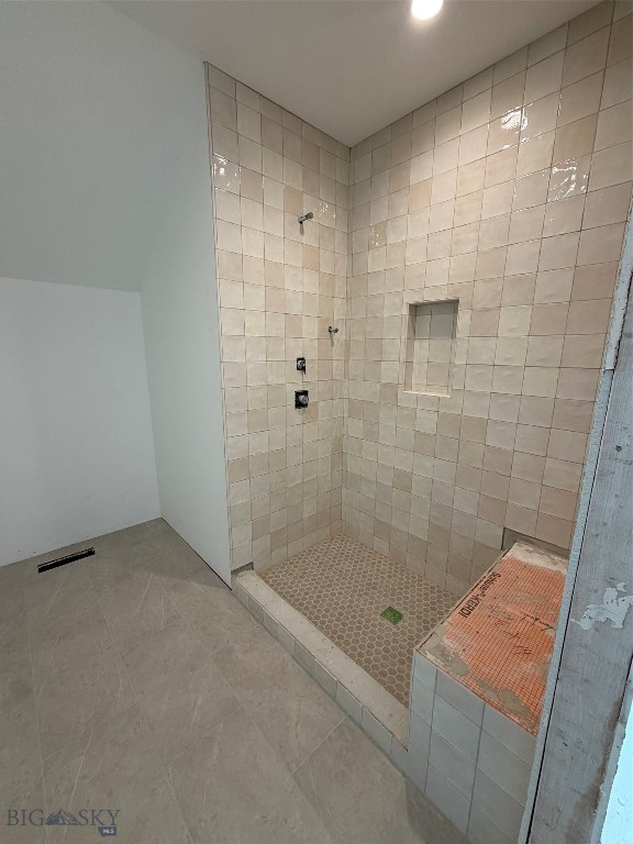 Walk-in shower with beige tiled walls, a mosaic floor, and a recessed niche.