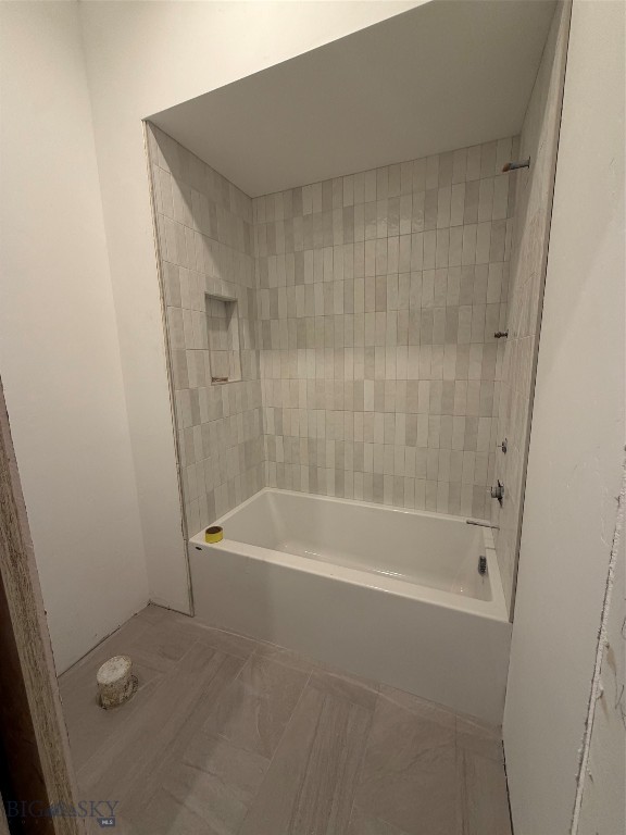 Unfinished bathroom with a white bathtub and pale tile surround and floor.