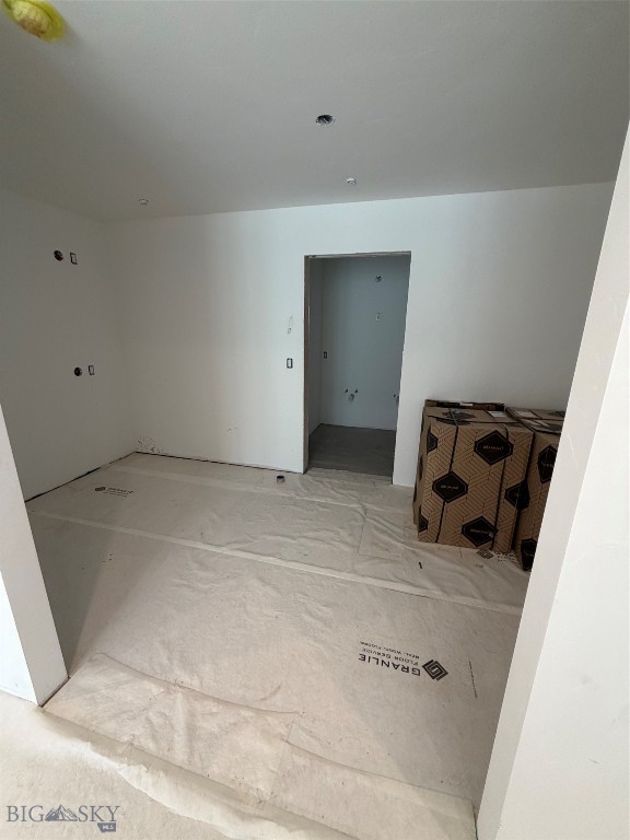 Unfinished interior room with protective floor covering and a doorway to another room.