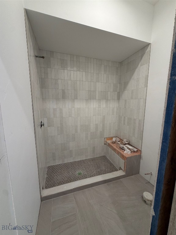 Walk-in shower under construction with pale tile walls, a hexagonal tile floor, and a built-in bench.