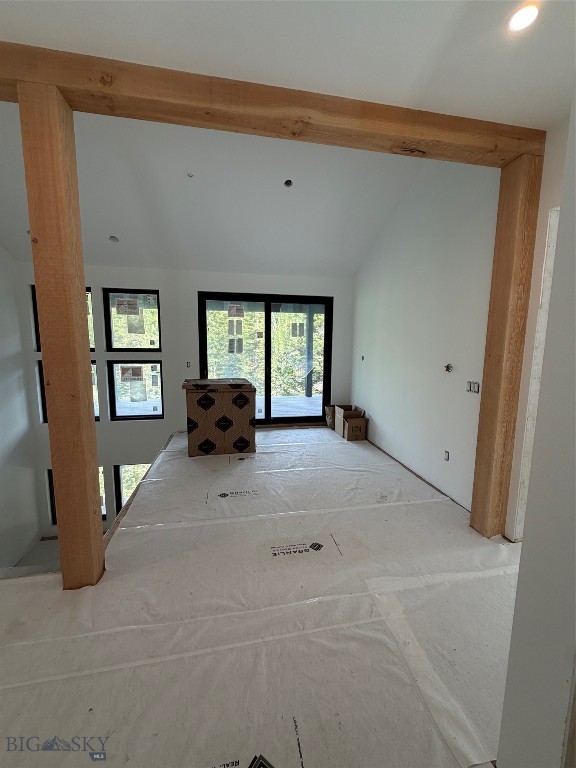 Unfinished interior with exposed wood framing, covered floors, and large windows and glass doors.