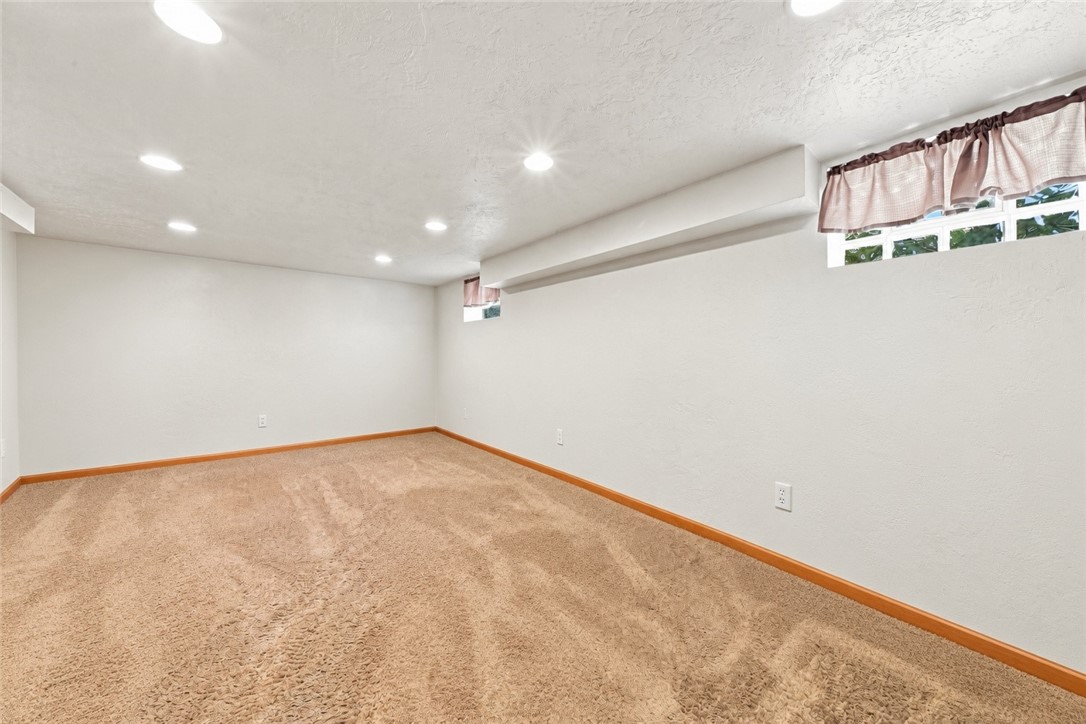 Empty carpeted room with recessed lights and high windows dressed with pink curtains.