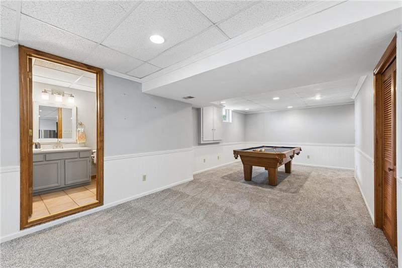 Basement recreation room with a pool table and an adjoining bathroom.