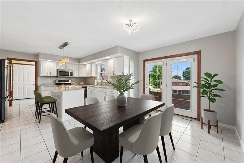 Open dining area with dark wood table beside a bright white kitchen and patio doors.
