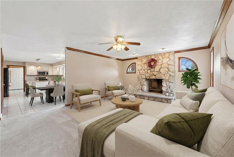 Living room with a stone fireplace, white sectional sofa, and open view to the kitchen.