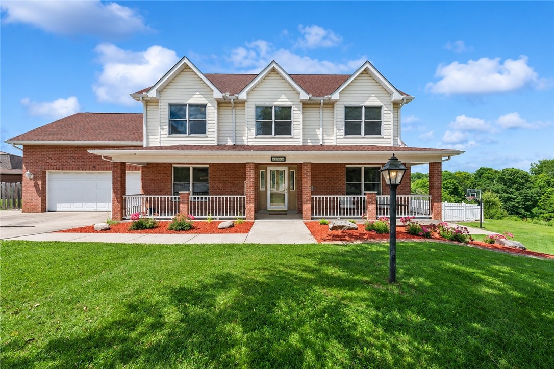 Two-story white-and-brick house with three front gables, a covered porch, and a broad green lawn.