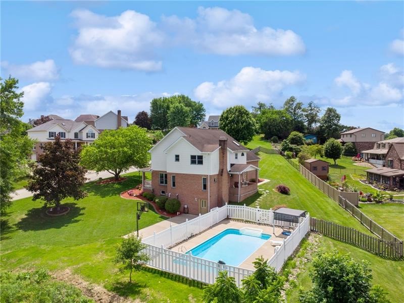 Aerial view of a two-story home with a fenced backyard and swimming pool.