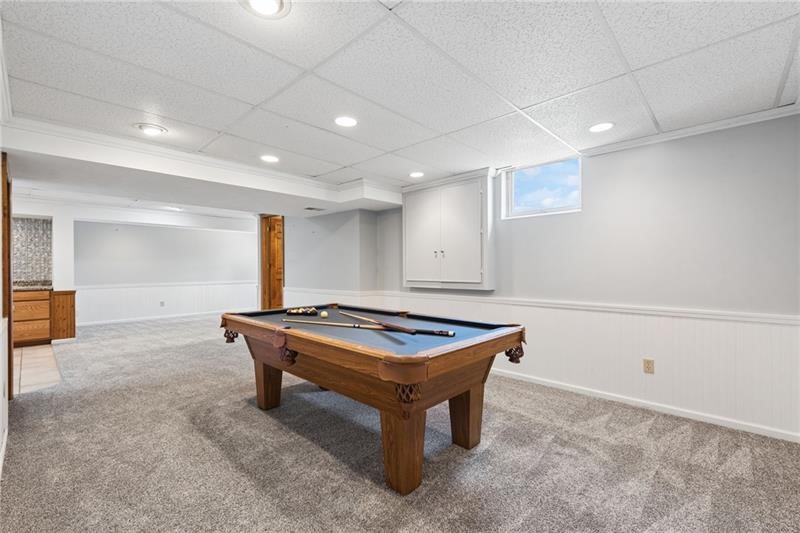 Finished basement game room with a wooden pool table and gray carpet.