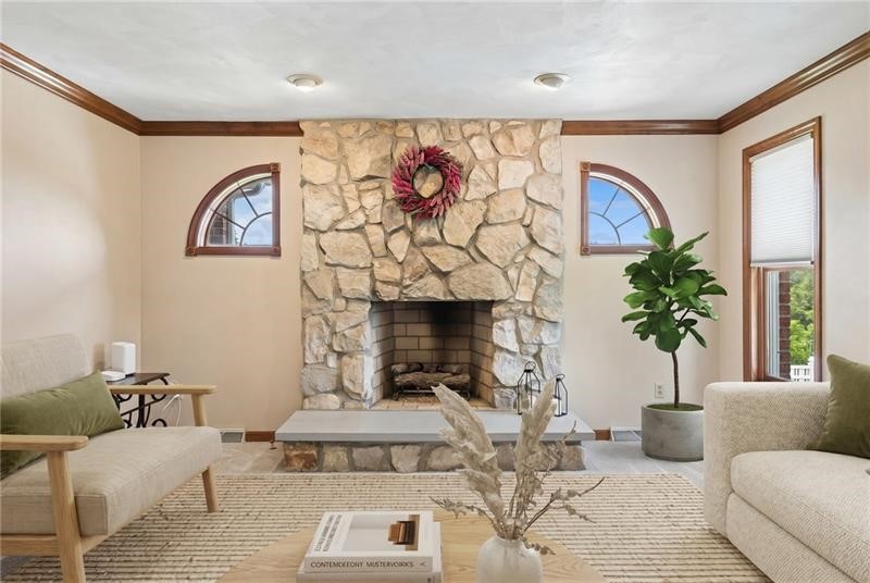 Living room with a stone fireplace, arched windows, and neutral sofas.