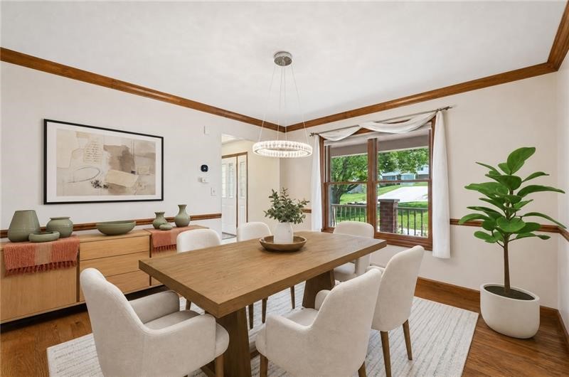 Dining room with a wooden table, upholstered chairs, and a broad window overlooking greenery.
