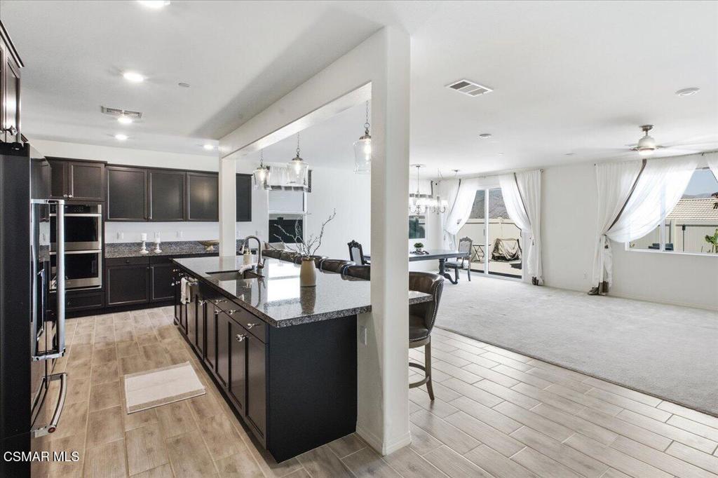 Open-plan kitchen with dark cabinets and granite island adjoining a bright living area.